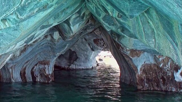 Exploring the sculpted chambers of the Marble Caves in Patagonia. Calm, turquoise waters reflect the magnificent striped rock formations under the daytime sun. A serene geological marvel.