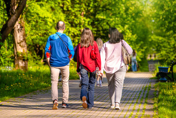 Obraz premium A man and two girls are walking in a city park 