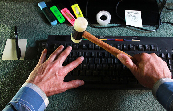 Romper ordenador con martillo maza a golpes en teclado error y enfado hammer hit keyboard laptop con virus y ciberataque en despacho oficina trabajo