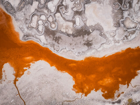 An orange river flows through a stark white landscape