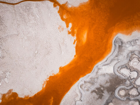 Orange mineral river flowing through white salt flats