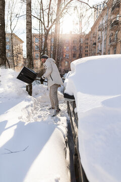 Man digging out his buried car from snow