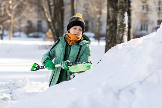 Young boy helps clear heavy snow from car