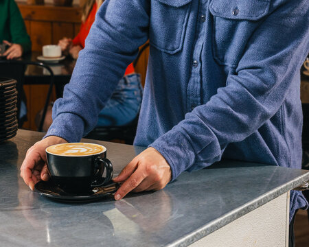 Barista placing a fresh latte on the counter