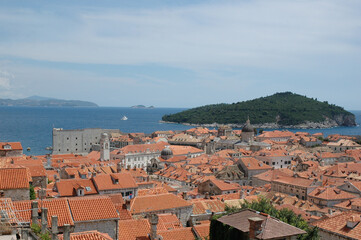 Fototapeta premium A scenic high angle view over the terracotta roofs of Dubrovnik Old Town showcasing Lokrum Island and the historic Saint John Fortress on the Adriatic Sea.