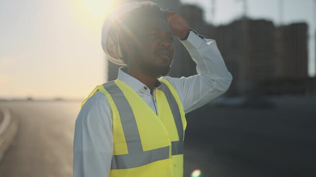 Building new district in outskirts, modern portrait of african american foreman. Hard hat for protective head and bright vest, builder professional in construction site, developing business center