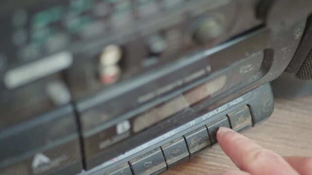 Nostalgic 90s analog electronics covered in heavy dust, pressing buttons on an obsolete cassette recorder.