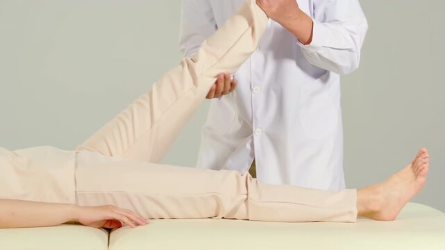 Elderly man massagist orthopedic specialist doctor helping women physical rehabilitation leg, hip treatment to female patient, doctor doing stretching disease treatment in the supine position.