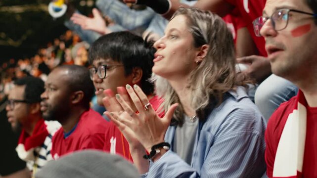 Female football supporter reacting with open hands and anxious face in red stadium crowd during dramatic live soccer match, anxious fans watching decisive final minutes, football equality.