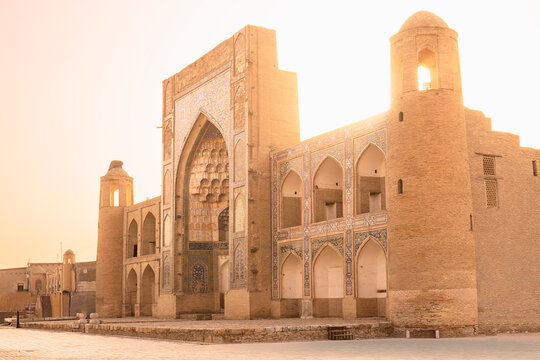 Abdulaziz Khan Madrasah facade in Bukhara bathed in golden sunset light. Historic Islamic architecture with ornate tilework and pointed arches in Uzbekistan. Ideal for travel publications.