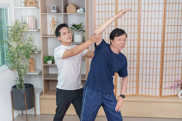 Obraz premium Asian man assisting senior with stretching exercise at home