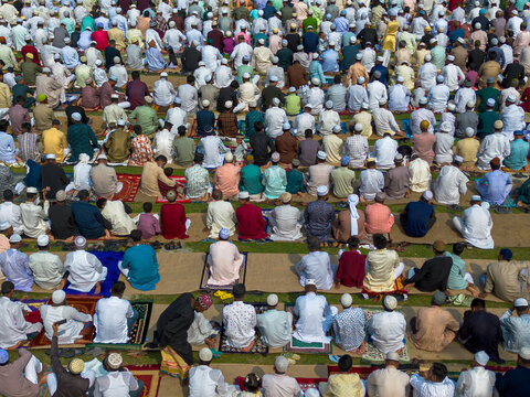 Joypurhat, Bangladesh - 28 May 2026: Aerial view of a large crowd of Muslim men gathered on prayer mats for Eid prayers in an open field.