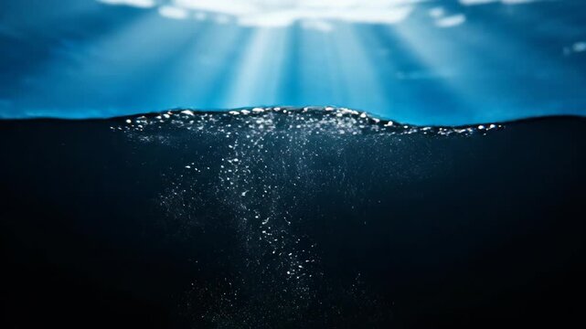 Underwater view of sunlight rays penetrating water surface with rising air bubbles. Aquatic scene showing light refraction and oxygen gas release in deep ocean