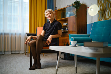 Obraz premium Woman sitting in chair with black stockings in modern living room during daytime