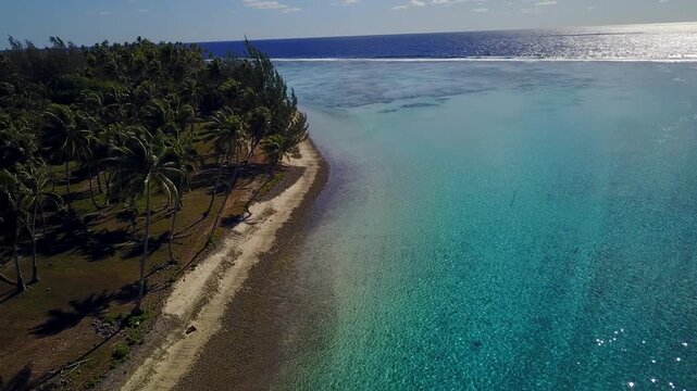 Aerial drone view of French Polynesia capturing turquoise lagoon waters, white sandy beaches and lush palm tree forests against green volcanic mountains. Islands Bora Bora, Huahine, Tahiti, Rangiroa