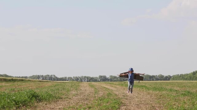 A happy child runs around the field with a toy jetpack