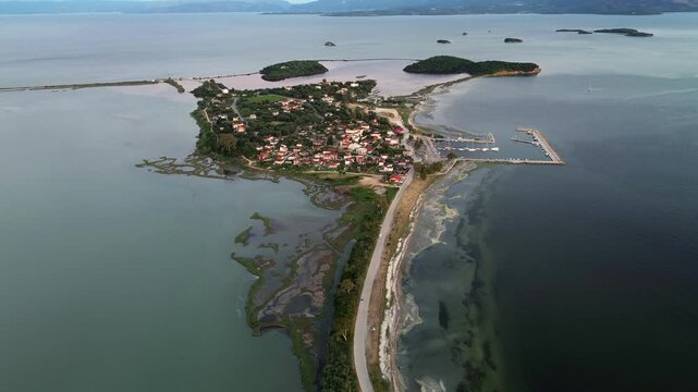 High angle drone shot following the coastal road leading to the unique Koronisia fishing village, isolated in the middle of Ambracian Gulf, Greece. High quality 4K travel footage.