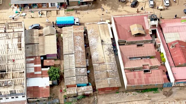 A cinematic view of rural Kenya showcasing informal settlements with rusted tin roofs, weathered homes, dusty village paths, and everyday community life.