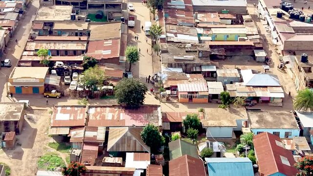 A cinematic view of rural Kenya showcasing informal settlements with rusted tin roofs, weathered homes, dusty village paths, and everyday community life.