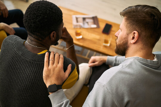 Young adult men supporting friend during group conversation, showing trust, empathy, male friendship. Useful for mental health, peer support, counseling, community campaigns