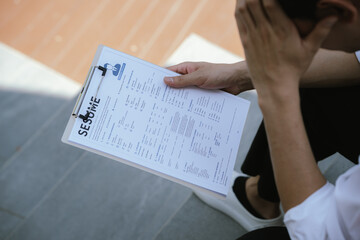 Naklejka premium Job applicant reviewing a resume document before an interview, reflecting career planning, employment opportunities, job search preparation, and professional development.