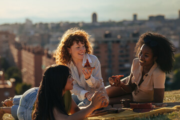 Obraz premium Diverse women friends sharing pizza picnic