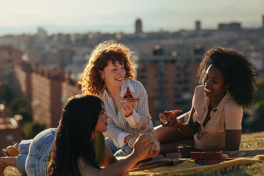 Diverse women friends sharing pizza picnic
