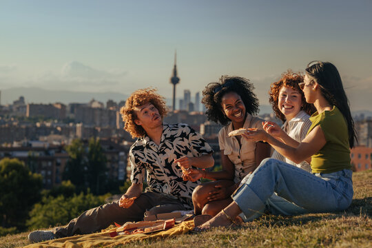 Friends having outdoor pizza picnic overlooking Madrid city