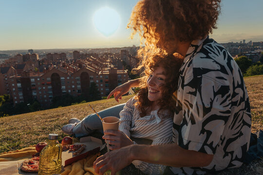 Couple enjoying picnic during sunset overlooking city