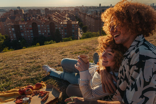 Happy couple enjoying romantic picnic with city views