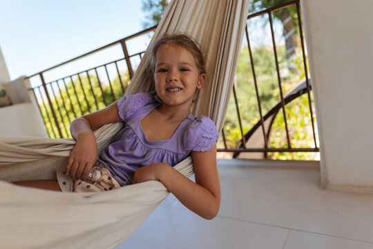 Smiling young girl relaxing in hammock on sunny terrace
