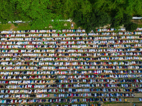 Joypurhat, Bangladesh - 28 May 2026: Aerial view of a large crowd of Muslim worshippers gathered in neat rows for outdoor prayers surrounded by lush green trees.