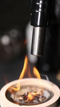 Barman encendiendo un ahumador de vidrio con soplete para un c&oacute;ctel. Barman profesional encendiendo un ahumador de virutas de madera con soplete. C&oacute;ctel ahumado, t&eacute;cnica de bar vanguardista.