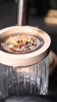 Barman encendiendo un ahumador de vidrio con soplete para un c&oacute;ctel. Barman profesional encendiendo un ahumador de virutas de madera con soplete. C&oacute;ctel ahumado, t&eacute;cnica de bar vanguardista.