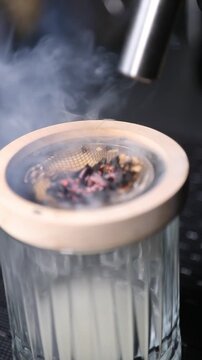 Barman encendiendo un ahumador de vidrio con soplete para un c&oacute;ctel. Barman profesional encendiendo un ahumador de virutas de madera con soplete. C&oacute;ctel ahumado, t&eacute;cnica de bar vanguardista.