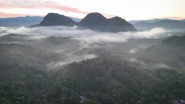 Aerial Drone View of Twin Peaks Above Morning Mist With Road at Pink Sunrise Meratus Mountains Borneo Indonesia