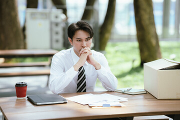 Fototapeta premium Young professional reviewing documents at an outdoor workspace, showing concern about employment, financial matters, career decisions, and business challenges.