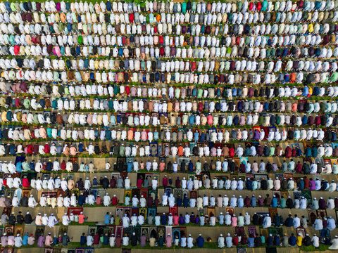 Joypurhat, Bangladesh - 28 May 2026: Aerial view of a large crowd of Muslim men performing mass prayer in neat rows on colorful mats during Eid celebrations.
