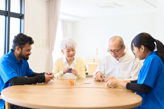 介護施設で折り紙を折るシニアと外国人介護士