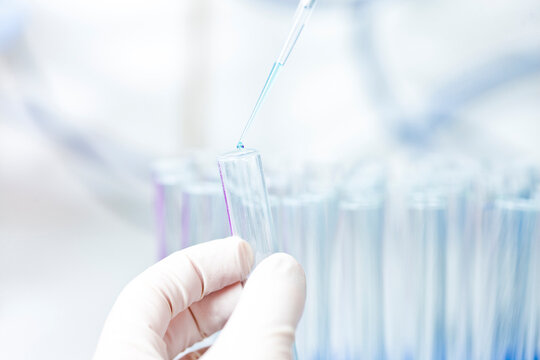 Germany, Human hand pipetting blue liquid into test tubes
