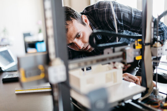Worker controlling a model, 3D printer