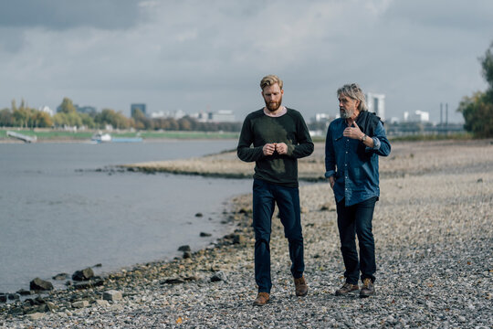 Father and son taking a stroll at Rhine river, meeting to talk