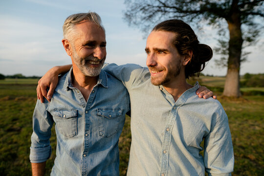 Happy father and adult son embracing on a meadow in the countryside