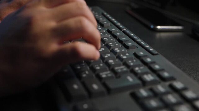 暗い部屋でパソコンのキーボードをタイピングするクリエイターの手元/Close-up of a creator's hands typing on a computer keyboard in a dark room