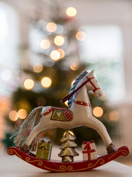 Nostalgic deocrative rocking horse before a lit Christmas tree
