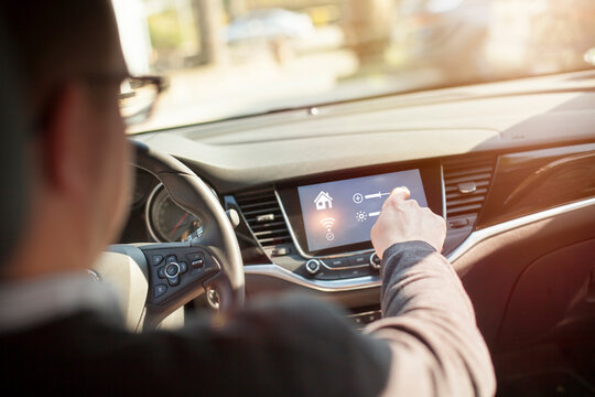 Man in car adjusting devices at home via smartphone