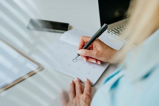 Businesswoman planning schedule in office with calendar