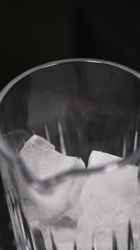 Barman colocando un cubo de hielo en una copa de c&oacute;ctel. Barman profesional a&ntilde;adiendo un cubo de hielo artesanal a una copa. Preparaci&oacute;n de c&oacute;cteles artesanales y servicio de bar premium.