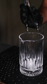 Barman colocando un cubo de hielo en una copa de c&oacute;ctel. Barman profesional a&ntilde;adiendo un cubo de hielo artesanal a una copa. Preparaci&oacute;n de c&oacute;cteles artesanales y servicio de bar premium.