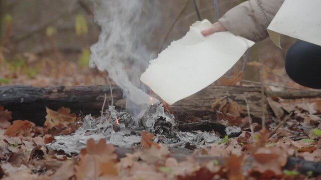 Sad woman burning letters on fire as a closure act of old life Smoke rising from freshly burned letters in quiet woodland, metaphor for cleansing memories